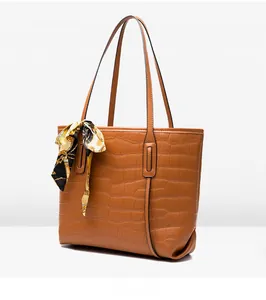 Close-up of brown crocodile texture tote bag with elegant floral silk scarf on handle