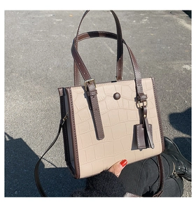 Detail of beige tote bag with crocodile pattern and stylish sphere tassel charms