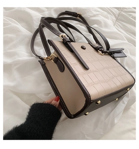 Detail of beige crocodile pattern tote bag with brown side panels and gold rivets