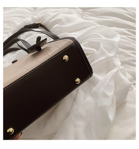 Detail of stone embossed tote bag showing metal feet studs and textured leather stitching