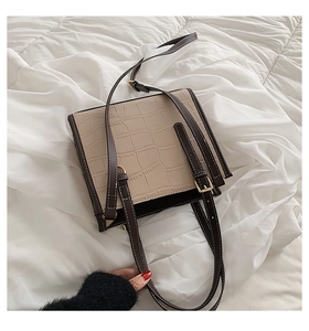 Detailed view of the stone embossed texture and brown leather straps on the beige tote bag