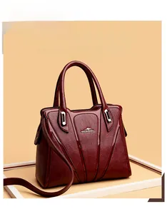 Detailed macro view of dark burgundy leather bag with triangle stitching and metal logo