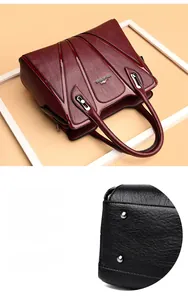 Detail of burgundy textured leather tote bag showing protective bottom metal rivets