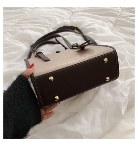Detail view of the bag's base showing gold-tone protective metal feet and mixed-tone texture