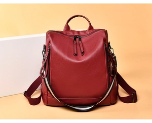 Dettaglio dello zaino in pelle bordeaux con borchie decorative e tracolla a righe