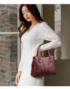 Detail view of burgundy leather handbag with metallic kangaroo logo and fine texture