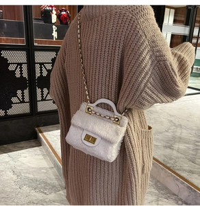 Vue détaillée du sac bandoulière en fausse fourrure blanche avec fermoir doré sur pull