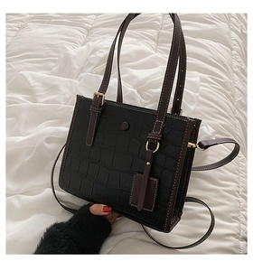 Detail of black crocodile pattern tote bag with white stitching and gold hardware