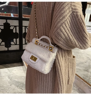 Gros plan d'un sac bandoulière en peluche blanche avec fermoir doré et chaîne