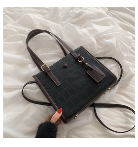 Detail view of the elegant crocodile pattern leather texture and gold buckle on this tote bag