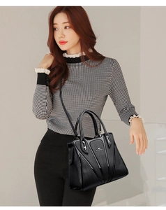 Detail of black pebbled leather tote with V-shaped design and metallic kangaroo logo