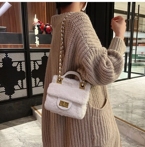 Détail du sac bandoulière en peluche blanche avec fermoir doré et sangle en chaîne