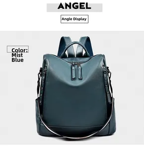 Vista frontale dello zaino in pelle blu nebbia con borchie metalliche e tasche laterali
