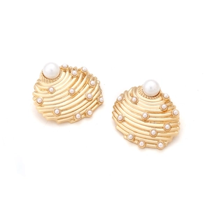 Détail de boucles d'oreilles coquillage dorées avec texture éventail et perles