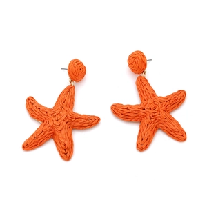 Detail of hand-woven orange raffia starfish earrings with natural textured finish