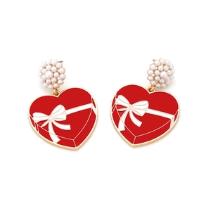 Detail of red heart earrings with white bow pattern and pearl clusters for women