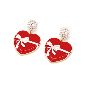Detail of red heart earrings with white bow pattern and pearl cluster studs