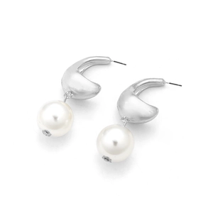 Detail of silver crescent metal earrings with round faux pearl drops on white background