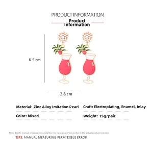 Detail of cocktail glass earrings with faux pearls and fruit charms on white background