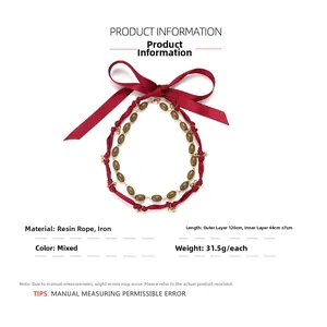 Detail of bohemian layered necklace with red ribbon bow and olive green resin beads