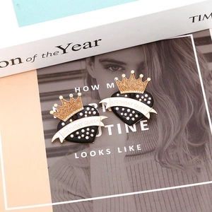 Detail of Birthday Queen heart earrings with black enamel and gold crown on magazines