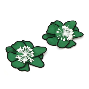 Détail de boucles d'oreilles fleurs en tissu vert fait main avec bords noirs et étamines