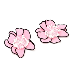 Détail de boucles d'oreilles fleurs en tissu rose avec pistils blancs et bords noirs