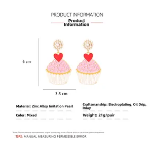 Detail of pink cupcake earrings with heart accents and faux pearls on zinc alloy