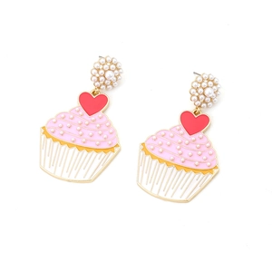 Detail of cupcake earrings with pink enamel, pearls and red heart charms on white background