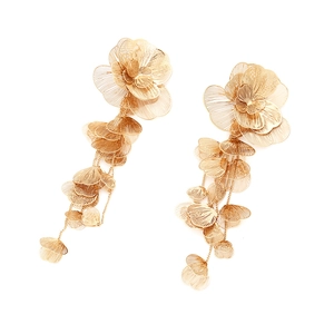 Gros plan de boucles d'oreilles fleurs dorées avec pompons et pétales en métal ciselé