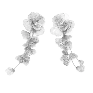 Vue macro de boucles d'oreilles fleurs en métal argenté avec détails de pompons