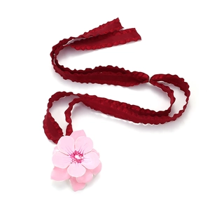 Pink enamel flower choker with deep red ruffled ribbon on a clean white background