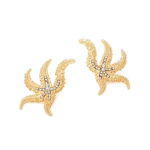 Macro shot of gold-plated starfish earrings with sparkling white rhinestones on white background