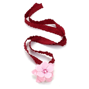 Pink enamel flower choker necklace with burgundy ruffled ribbon on white background