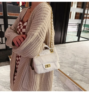 Détail d'un sac à bandoulière en peluche blanche avec fermoir doré et chaîne élégante