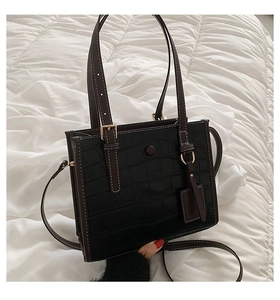 Close-up of black crocodile pattern tote bag with brown handles and gold hardware