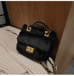 Détail d'un sac à main noir en fausse fourrure avec fermoir doré et bandoulière chaîne