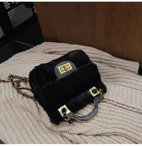 Détail du sac à main en fausse fourrure noire avec fermoir doré et bandoulière chaîne