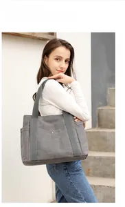 Dettaglio della borsa tote in tela grigia capiente con tasche laterali e manico