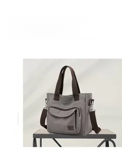 Detail of taupe canvas tote bag showing front flap pocket and adjustable shoulder strap