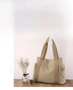 Dettaglio borsa tote in tela kaki con design multitasca e bottone automatico in metallo