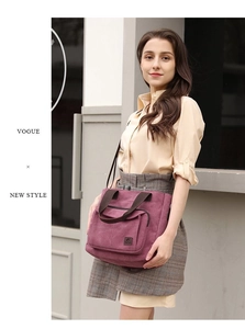 Detail of dark purple canvas tote bag with brown handles and a zip front pocket