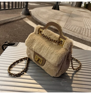 Détail du sac bandoulière en peluche avec fermoir doré et texture fourrure sur valise argent