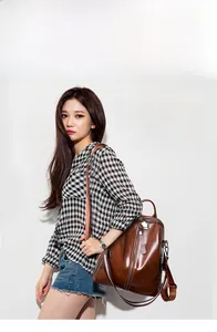 Brown vintage leather backpack with adjustable striped fabric straps on a model