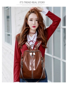 Detail of vintage brown soft leather backpack with vertical zipper and metal charm