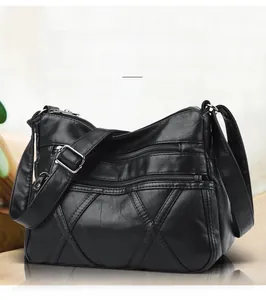 Close-up of black crossbody bag with multi-zipper pockets and geometric stitching detail