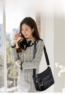 Détail d'un sac bandoulière en cuir PU noir avec gaufrage floral et poches zippées multiples
