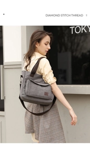 Detail of adjustable strap and front pocket on gray canvas messenger bag in urban setting