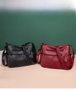 Detail of embossed floral texture and dual zipper pockets on black and maroon leather bags