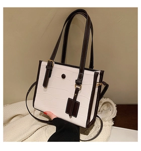 Detail shot of the crocodile-embossed white leather and coffee brown tote bag trim